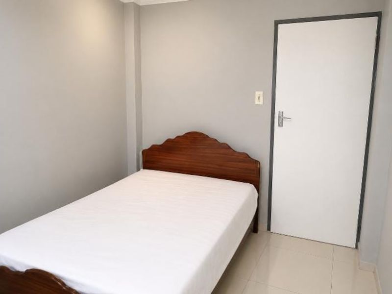 A simple bedroom featuring neutral grey walls and tiled flooring, providing a clean and functional space.