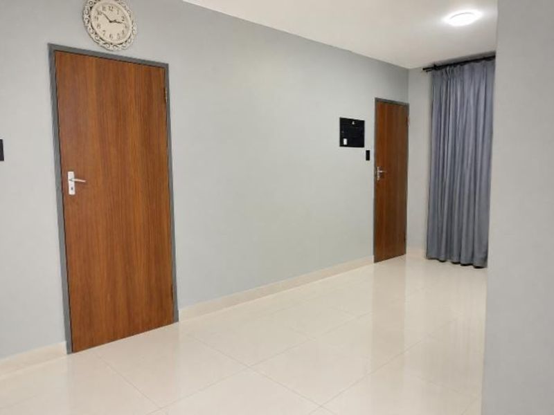 A clean and well-maintained hallway featuring neutral wall tones, polished tiled flooring, and recessed ceiling lighting, providing access to multiple rooms.