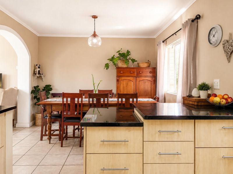 Open-plan kitchen and dining area featuring light wood cabinetry, granite countertops, tiled flooring, and a classic architectural archway connecting the spaces.