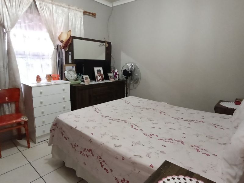 A functional bedroom featuring tiled flooring and a window with curtain rod, providing a neutral base for potential interior updates.