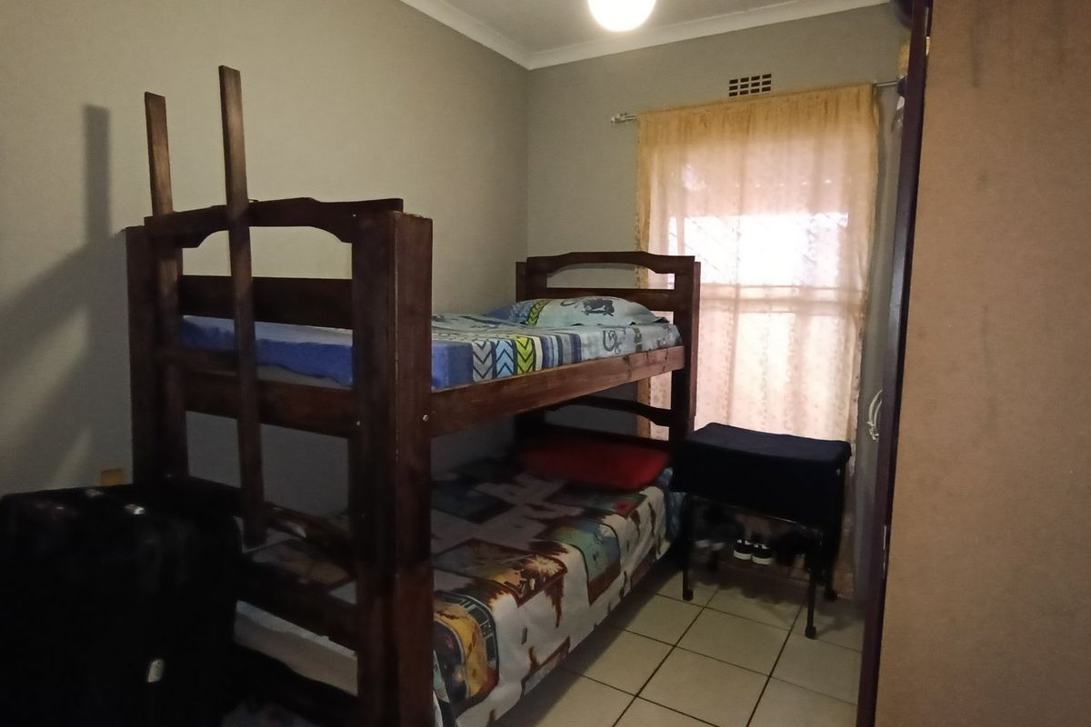A functional bedroom featuring tiled flooring and a built-in cupboard, providing essential storage space.