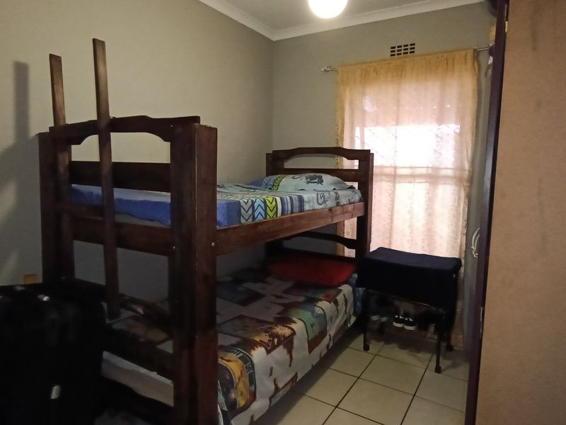 A functional bedroom featuring tiled flooring and a built-in cupboard, providing essential storage space.