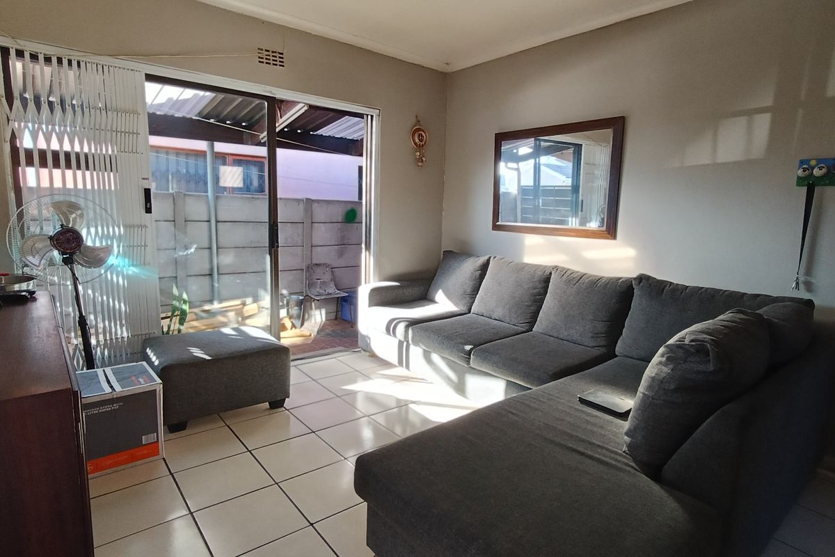 A living room featuring ceramic floor tiles and a sliding glass door providing access to an outdoor patio area.