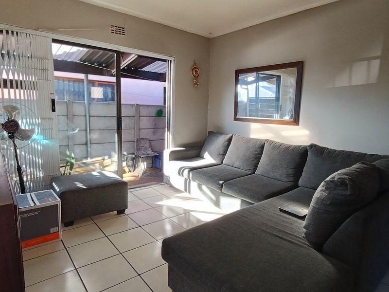 A living room featuring ceramic floor tiles and a sliding glass door providing access to an outdoor patio area.