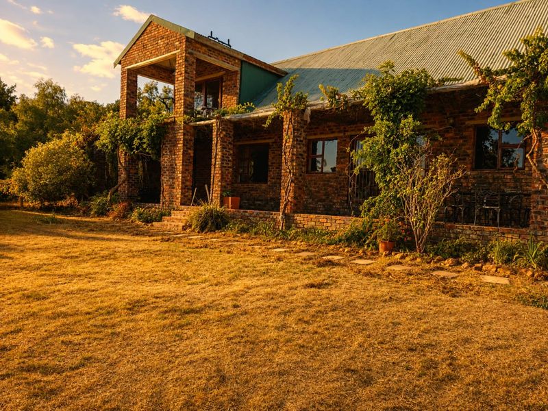 A charming rustic house featuring exposed brickwork, a corrugated metal roof, and a spacious covered patio overlooking a large garden area.