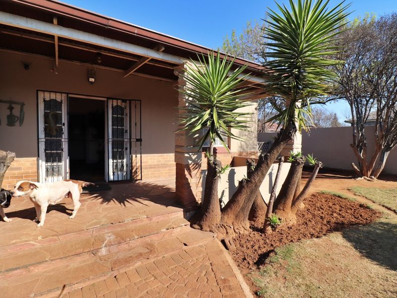 A covered outdoor patio area featuring stone paving and brick pillars, providing a functional transition space between the home and the garden.