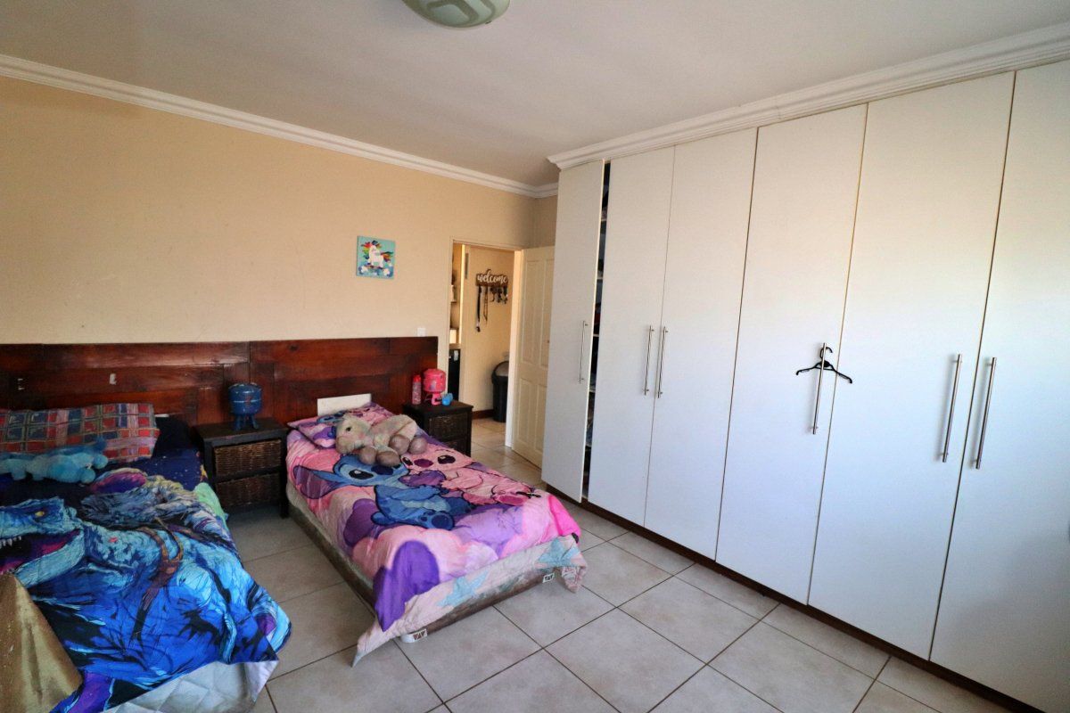 A bedroom featuring tiled flooring, coved ceilings, and extensive white built-in cupboards providing ample storage space.