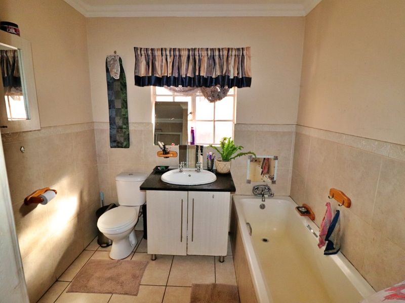 A functional bathroom featuring a vanity with basin, a standard toilet, and a bathtub with tiled wall surrounds and flooring.