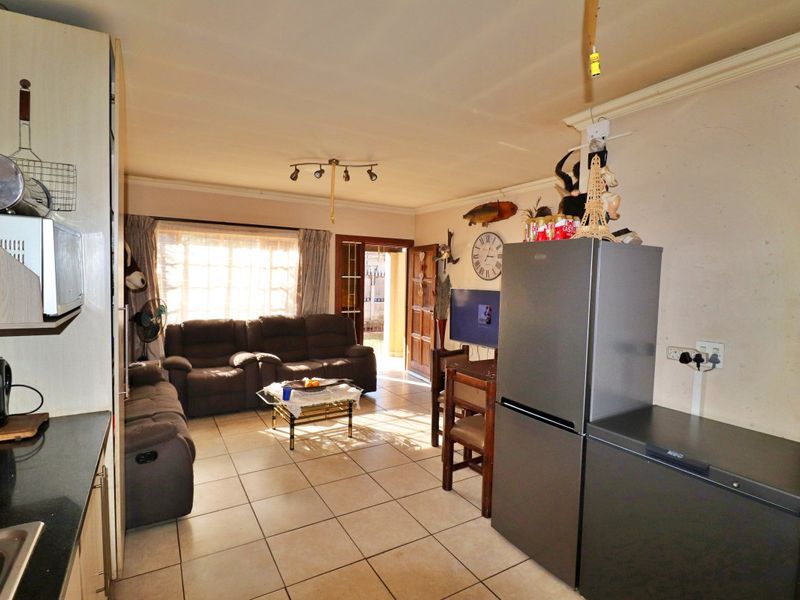 Open plan living and kitchen area featuring tiled flooring, built-in cabinetry, and direct access to the exterior through a timber door.