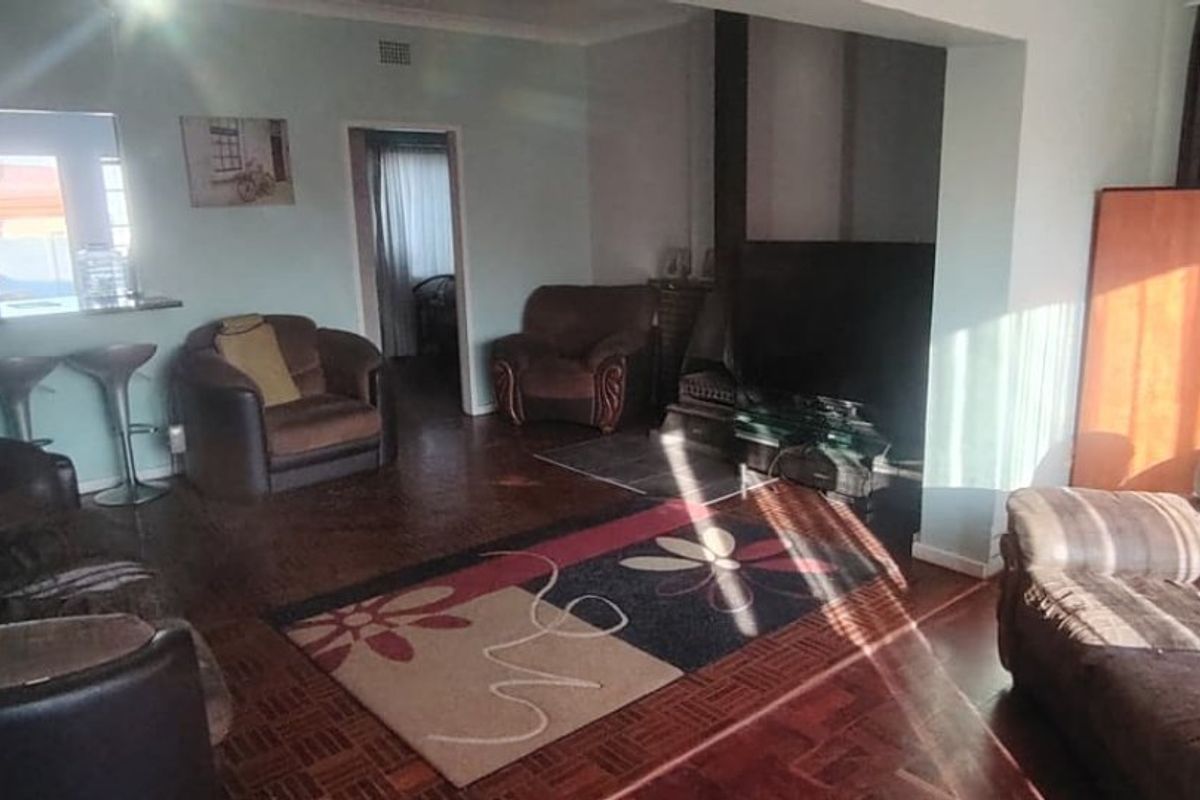 Spacious living room featuring traditional parquet flooring, a built-in fireplace, and an open-plan breakfast bar connecting to the kitchen area.