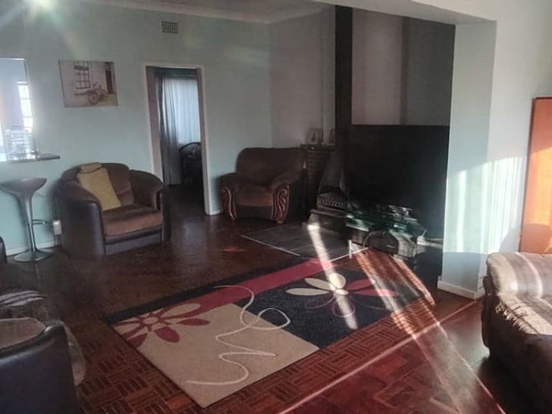Spacious living room featuring traditional parquet flooring, a built-in fireplace, and an open-plan breakfast bar connecting to the kitchen area.