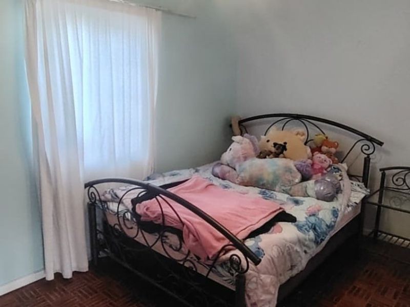 A bedroom featuring parquet flooring and light-colored walls, providing a functional space with natural light from the window.