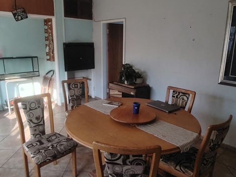 A dining area featuring tiled flooring and a wall-mounted television, requiring cosmetic updates to improve the overall aesthetic and finish.