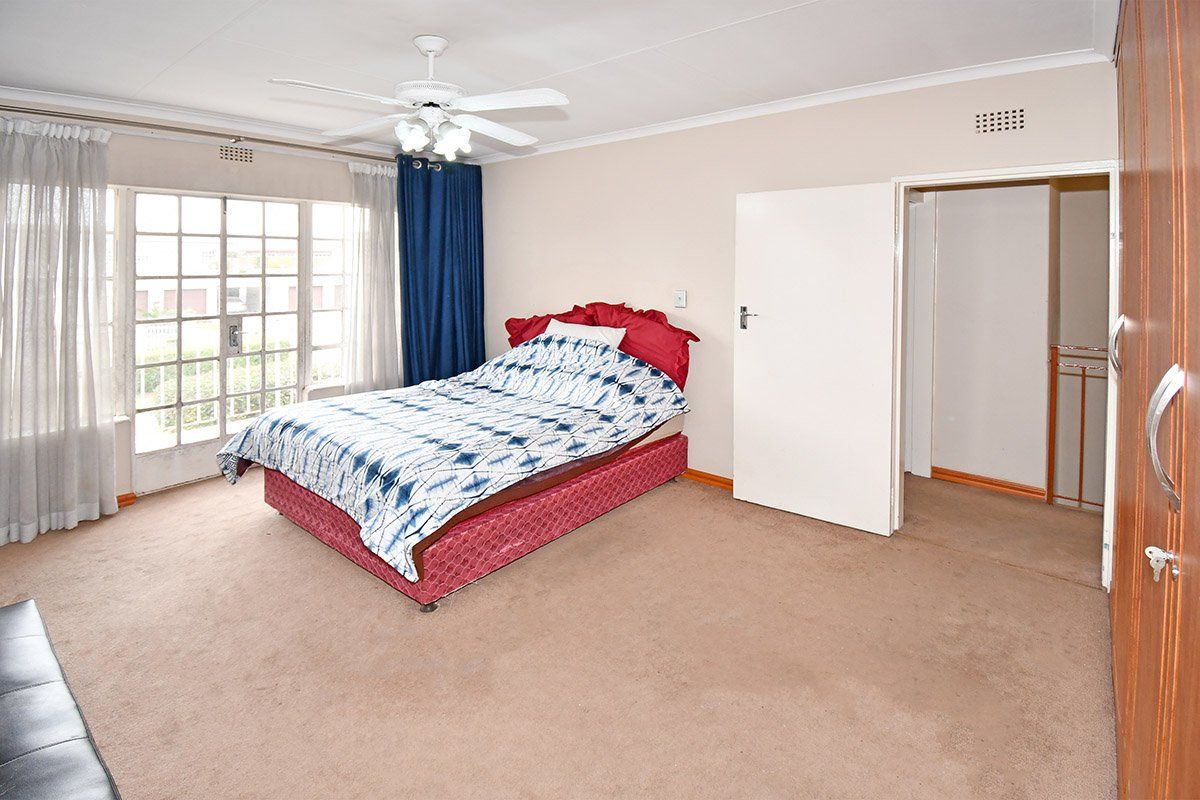 Spacious bedroom featuring carpeted flooring, built-in cupboards, a ceiling fan, and direct access to an outdoor area through glass french doors.