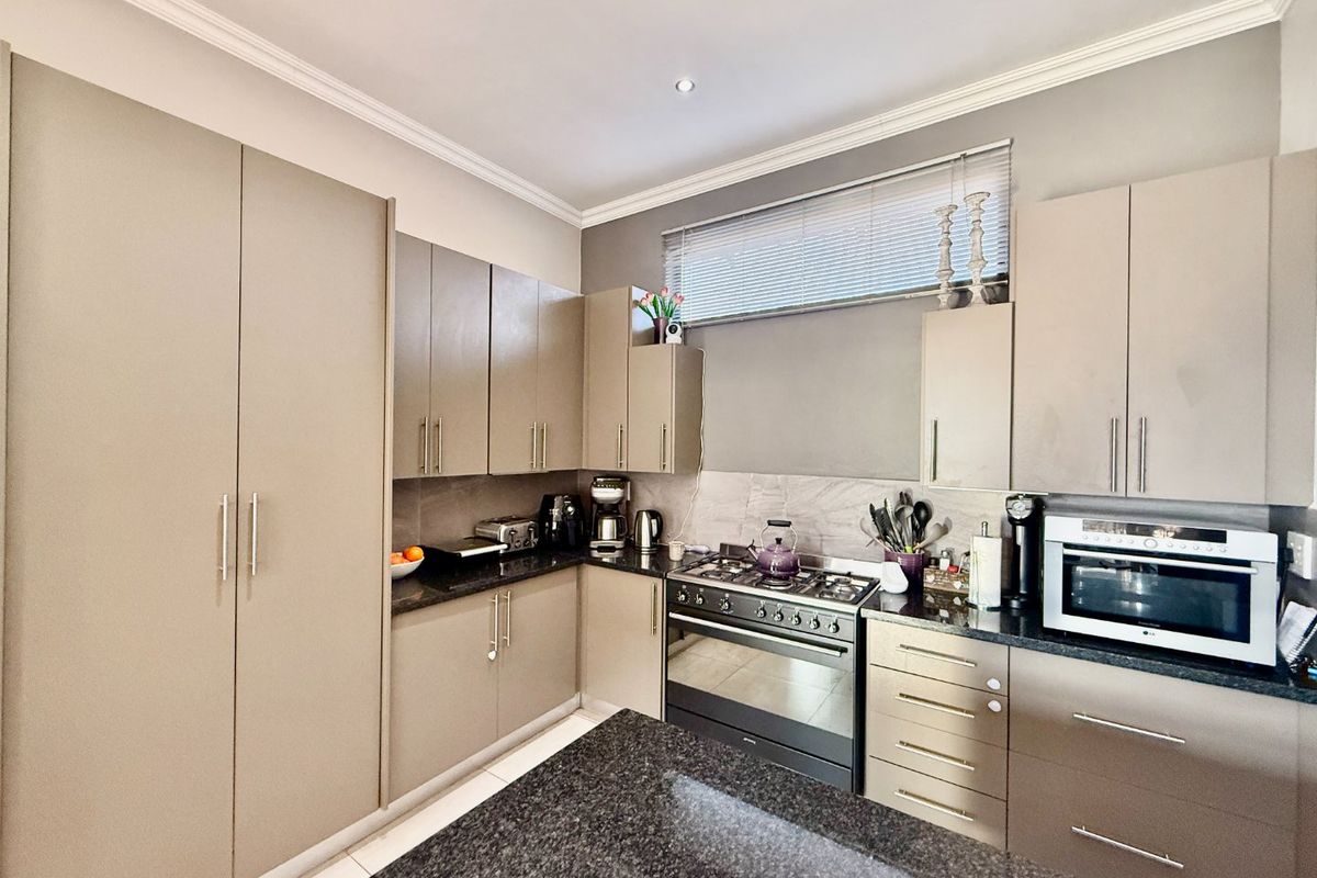 Modern kitchen featuring sleek built-in cabinetry, granite countertops, a gas stove with extractor, and high-quality finishes throughout.