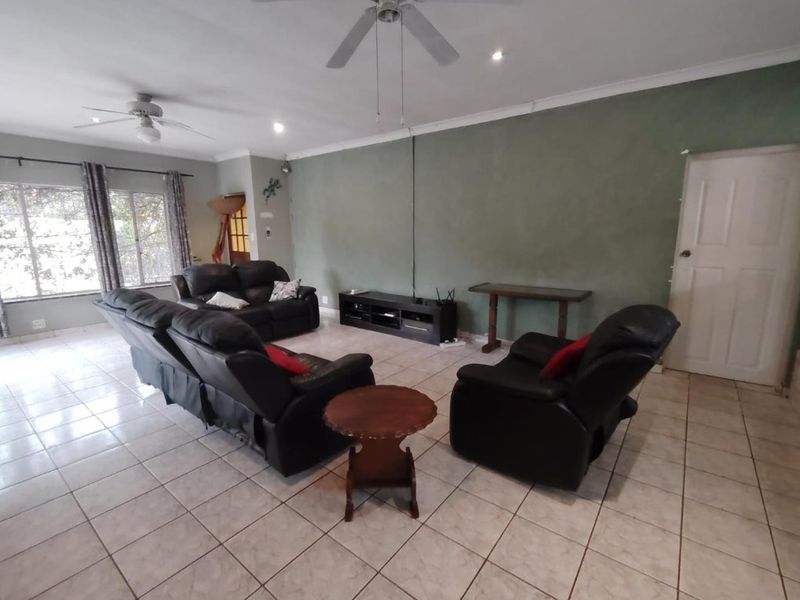 Spacious living room featuring tiled flooring, ceiling fans, and neutral wall finishes, offering a functional and comfortable layout for relaxation.