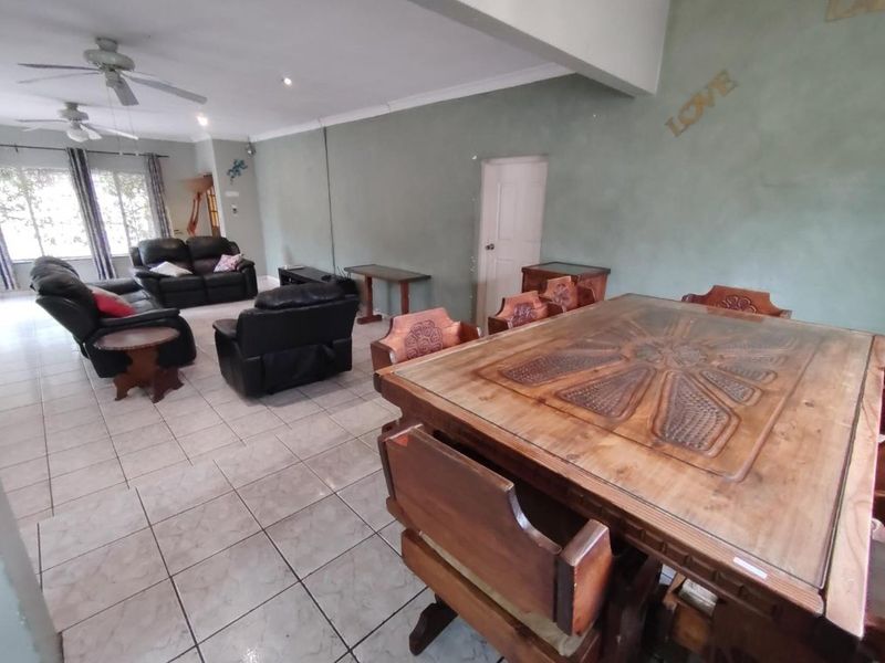 Spacious open-plan living and dining area featuring neutral tiled flooring, ceiling fans, and recessed lighting, offering a versatile layout for family living.