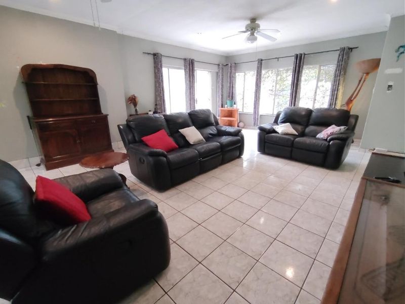 Spacious living room featuring neutral tiled flooring, a ceiling fan, and large sliding glass doors providing ample natural light.