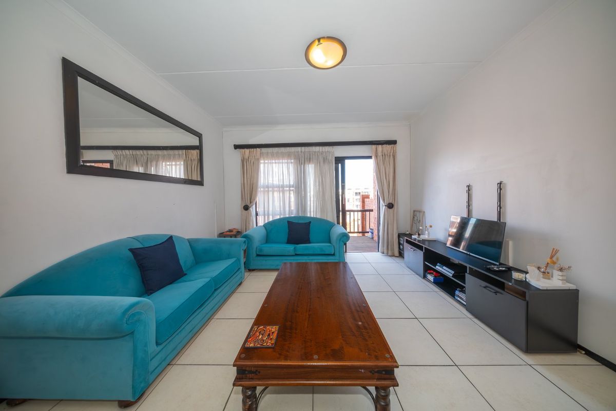 A bright living room featuring tiled flooring and a sliding glass door providing access to an outdoor balcony area.