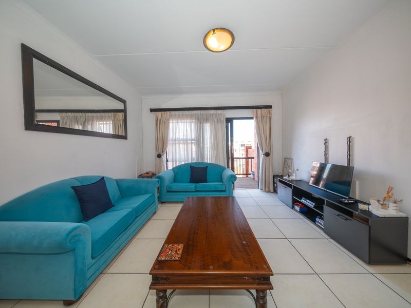 A bright living room featuring tiled flooring and a sliding glass door providing access to an outdoor balcony area.