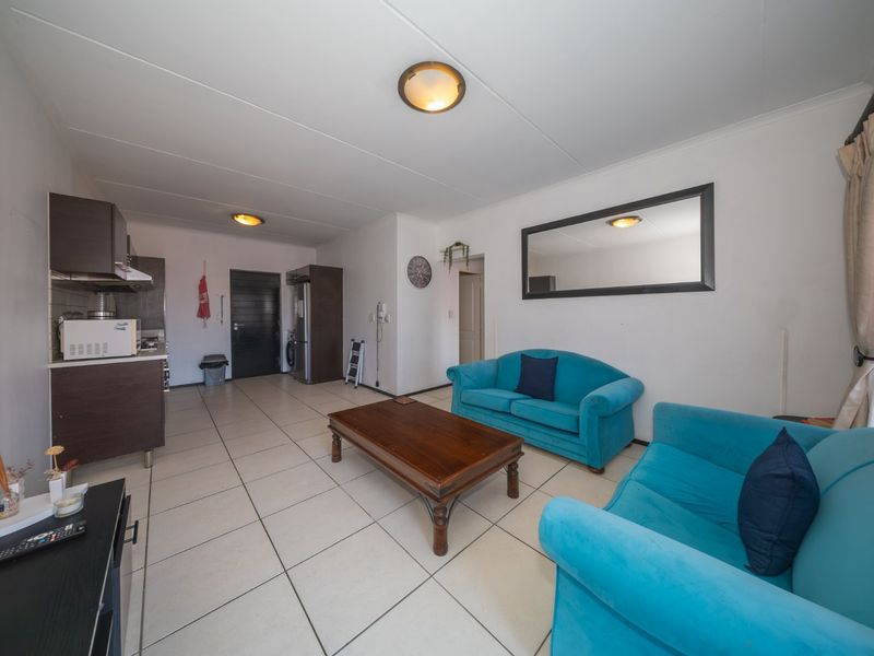 Open-plan living area featuring tiled flooring and a compact kitchen with built-in cabinetry, creating a functional and connected space.
