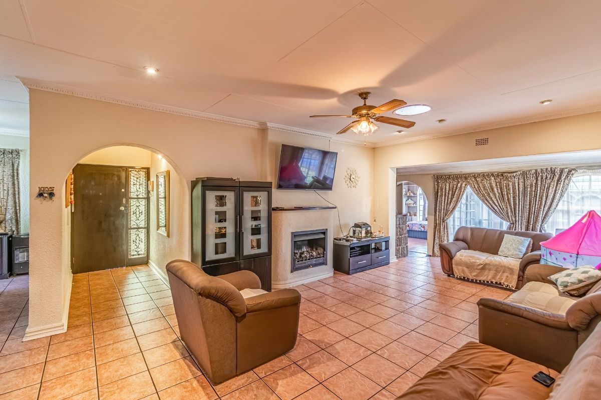 Spacious living room featuring tiled flooring, a built-in fireplace, and an arched entryway, offering a comfortable and functional layout.