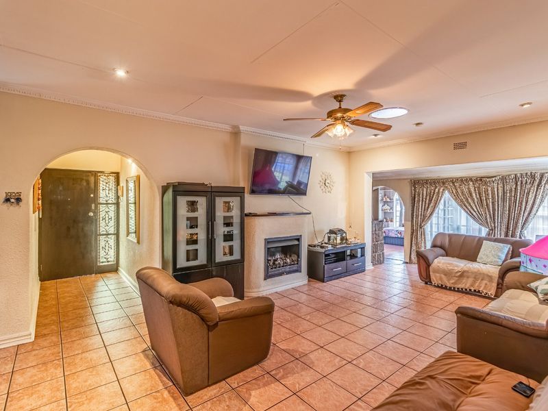 Spacious living room featuring tiled flooring, a built-in fireplace, and an arched entryway, offering a comfortable and functional layout.