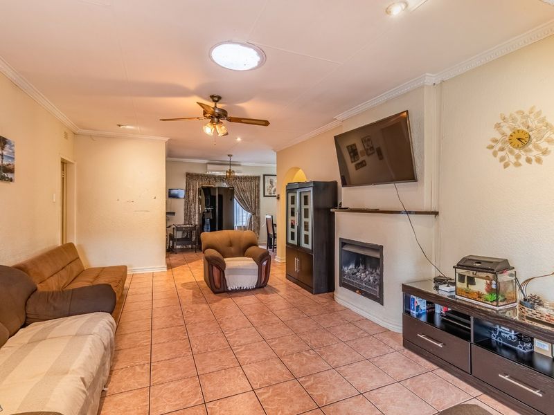 Spacious living room featuring tiled flooring, a built-in fireplace, ceiling fan, and a skylight, offering a comfortable and functional living space.