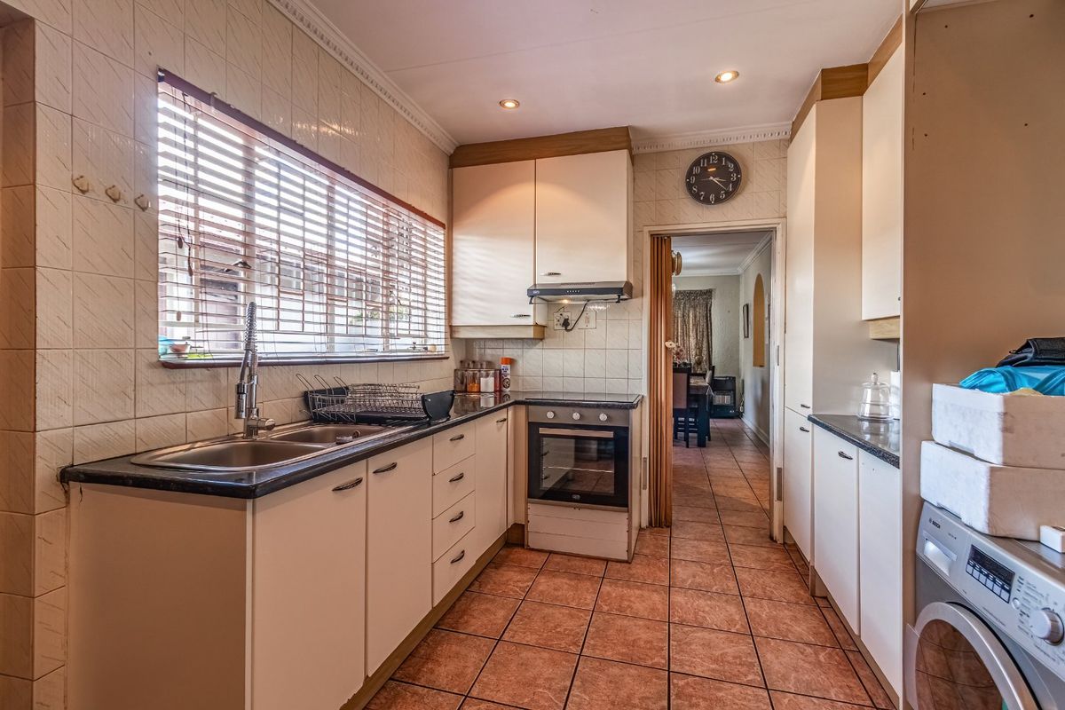 A functional kitchen featuring built-in cabinetry, laminate countertops, a built-in oven with extractor fan, and tiled flooring throughout.