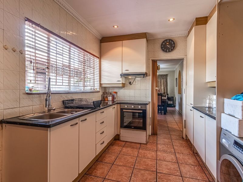 A functional kitchen featuring built-in cabinetry, laminate countertops, a built-in oven with extractor fan, and tiled flooring throughout.
