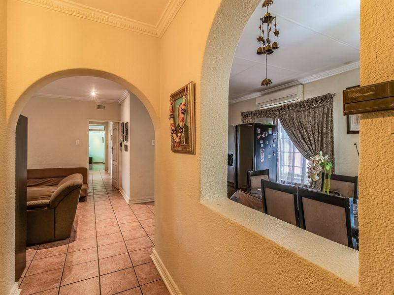 Open-plan living and dining area featuring arched architectural details, tiled flooring, and a wall-mounted air conditioning unit.