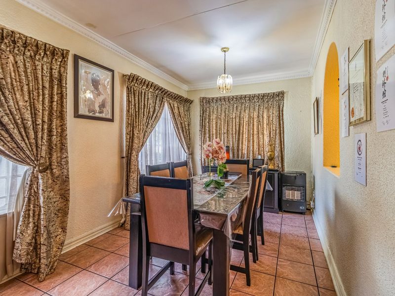 A dining room featuring tiled flooring, decorative cove cornicing, and a feature archway, providing a functional space for family meals.