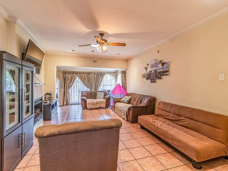 A spacious living room featuring tiled flooring, a ceiling fan, and a built-in fireplace, offering a comfortable and functional living area.