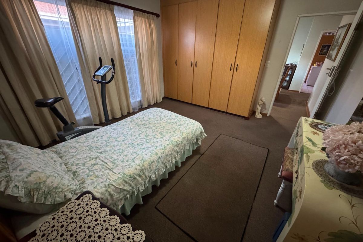 A bedroom featuring built-in wooden cupboards and carpeted flooring, offering a functional space with potential for modern updates.