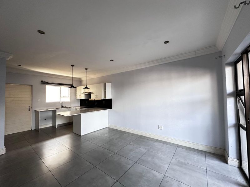 Open-plan living area featuring a modern kitchen with built-in cabinetry, a breakfast island, tiled flooring, and recessed lighting throughout.