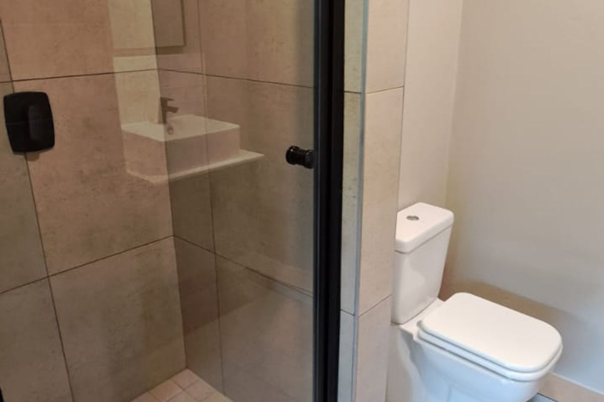 A clean, modern bathroom featuring a glass-enclosed shower with tiled walls and a standard white toilet.