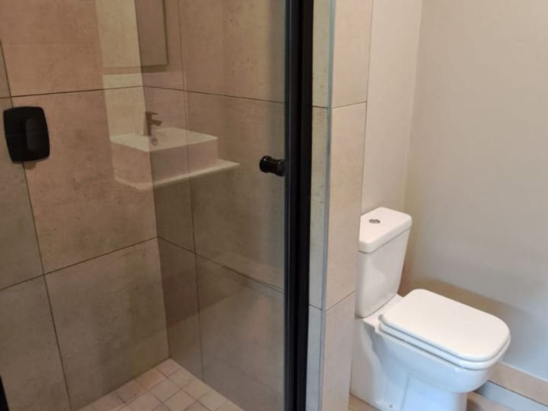 A clean, modern bathroom featuring a glass-enclosed shower with tiled walls and a standard white toilet.