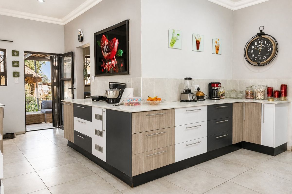 Modern kitchen featuring two-tone cabinetry, stone countertops, and tiled flooring, with direct access to an outdoor patio area.