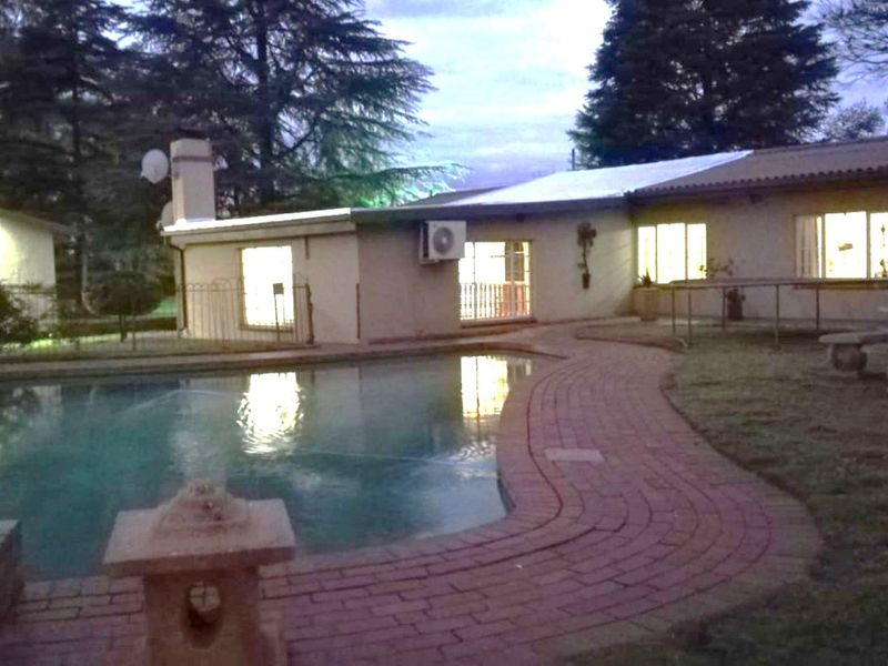 Exterior view of a farm property featuring a swimming pool, brick paved surround, and multiple air conditioning units mounted on the building facade.