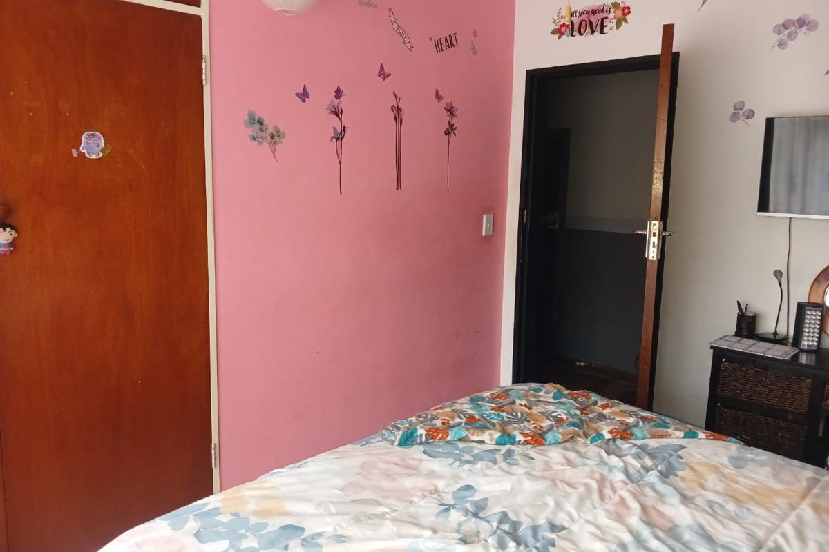A bedroom featuring a built-in wardrobe and a standard internal door, with pink accent wall paint.