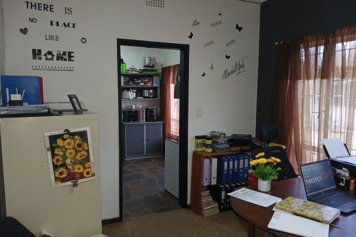 A living area featuring stone flooring and a doorway leading into a secondary kitchen or scullery space.