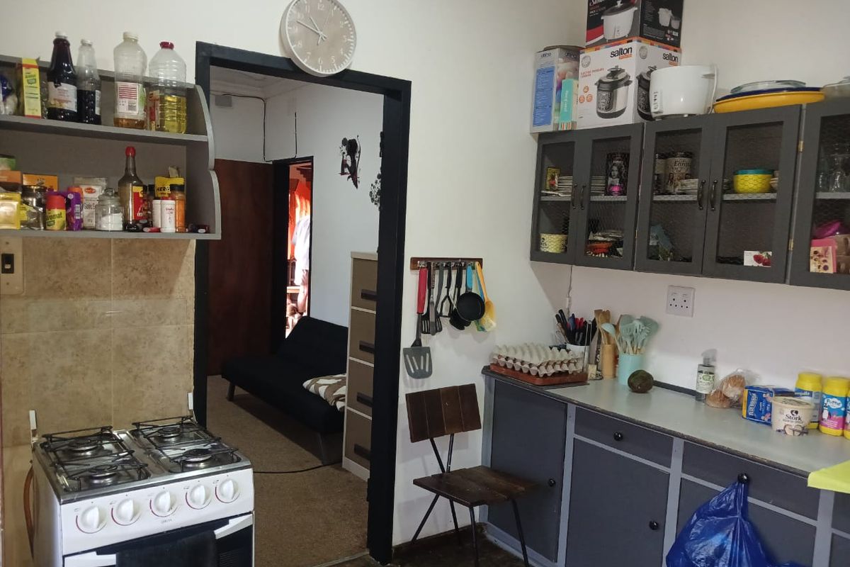 A functional kitchen featuring a gas stove, tiled splashback, and grey built-in cabinetry with overhead storage units.