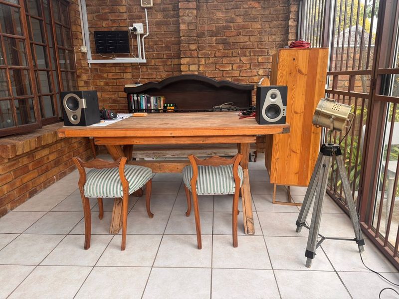 A covered patio area featuring exposed brick walls, tiled flooring, and large timber-framed windows, providing a versatile outdoor living space.