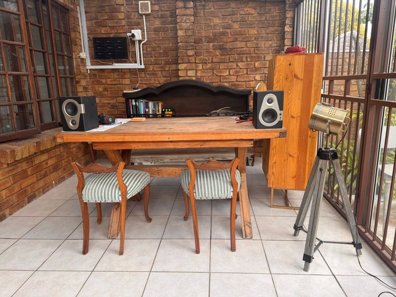 A covered patio area featuring exposed brick walls, tiled flooring, and secure metal framing, suitable for use as a casual dining or workspace.