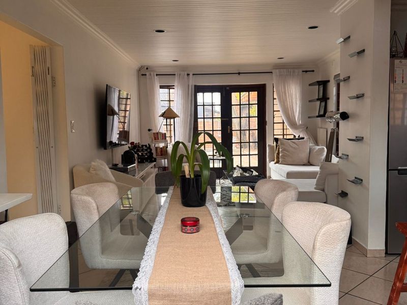 Open-plan living and dining area featuring tiled flooring, tongue and groove ceiling, track lighting, and French doors leading to the exterior.