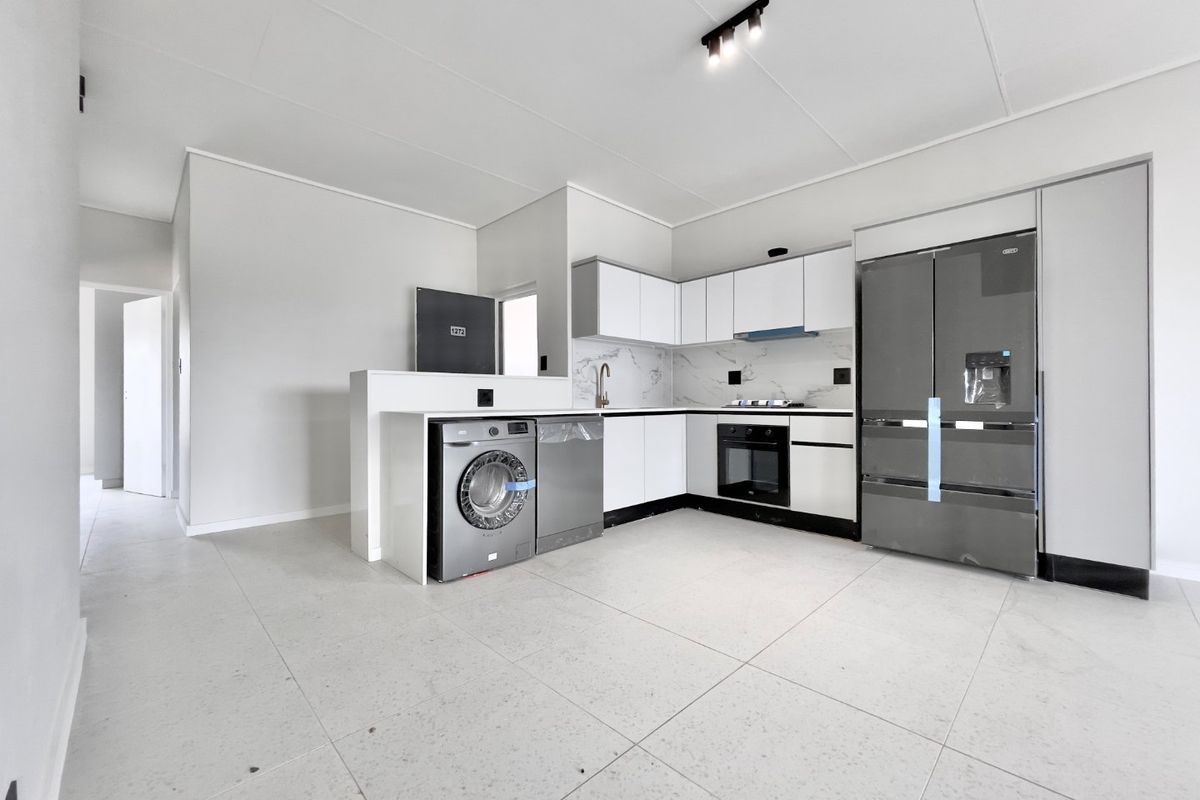 Modern, clean-lined kitchen featuring white cabinetry, marble-look backsplash, integrated appliances, and large format floor tiles in an open-plan layout.