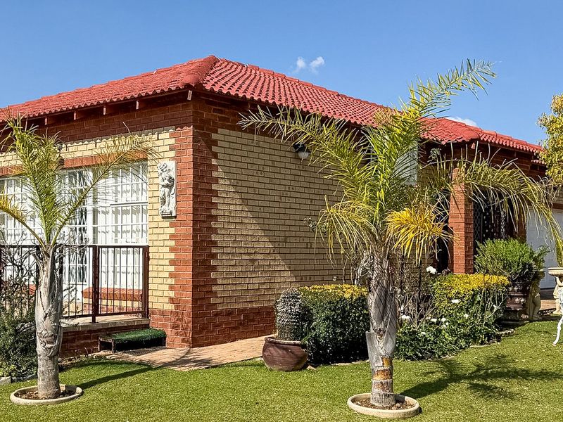 A well-maintained townhouse featuring a classic facebrick exterior, red tiled roof, and established garden surroundings.