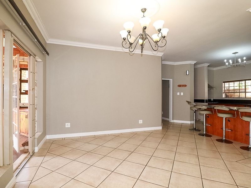 Spacious open-plan living and dining area featuring tiled floors, crown molding, a breakfast bar, and sliding doors leading to an outdoor space.