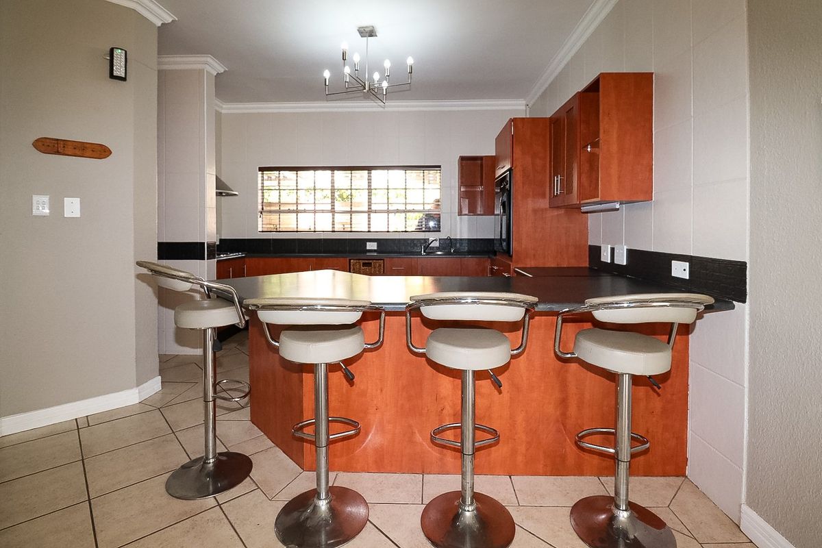 A functional kitchen featuring wooden cabinetry, a breakfast bar, tiled flooring, and built-in appliances, offering a practical layout for daily cooking and dining.