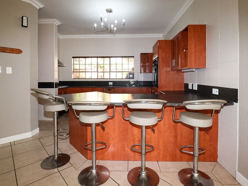 A functional kitchen featuring wooden cabinetry, a breakfast bar, tiled flooring, and built-in appliances, offering a practical layout for daily cooking and dining.